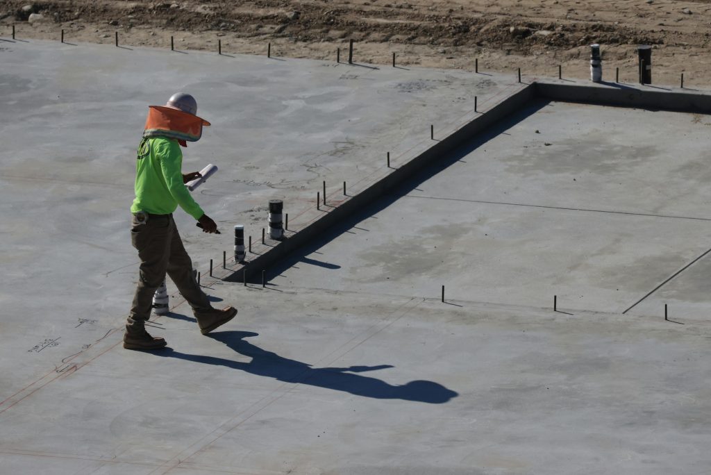 inspector checking steel reinforcement cover and spacing before concrete slab pour